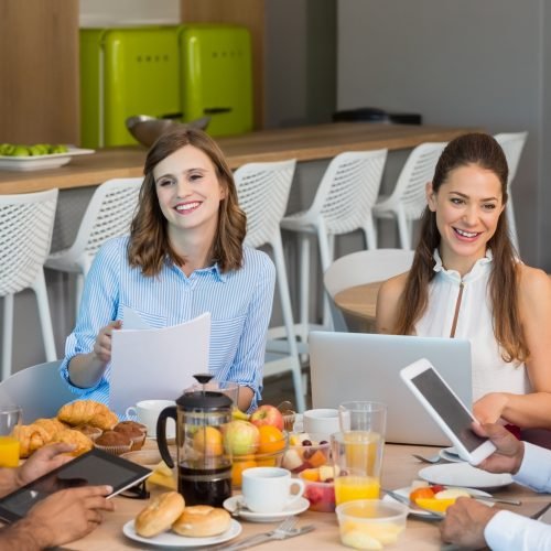 Business colleagues discussing over digital tablet while having breakfast